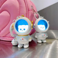 Llaveros kawaii astronauta con diseño de oso blanco y detalles dorados junto a mochila rosa