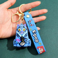 Llaveros K-pop con figura de gato azul estilizado y correa decorativa de silicona en mano